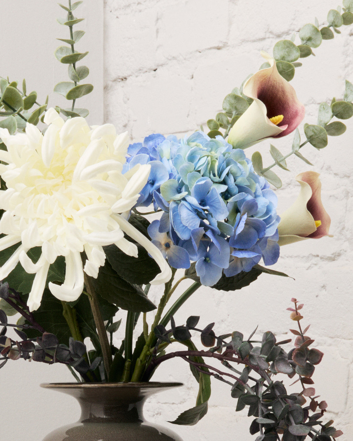 Närbild av konstgjorda blommor i buketten Blue Hour med blå hortensia, vit krysantemum och vita kallor med lila detaljer.